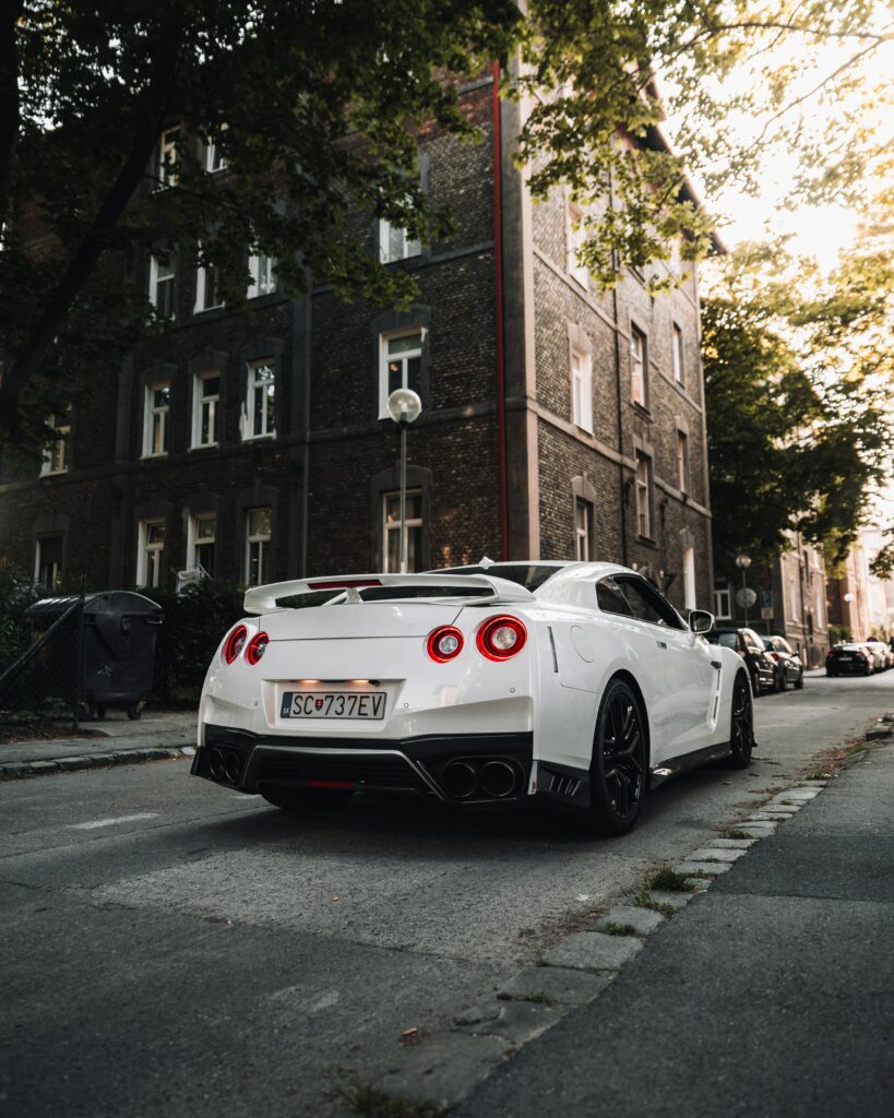 Sleek Nissan GT-R: Urban Elegance Amidst Historic Brick & Greenery Wallpaper