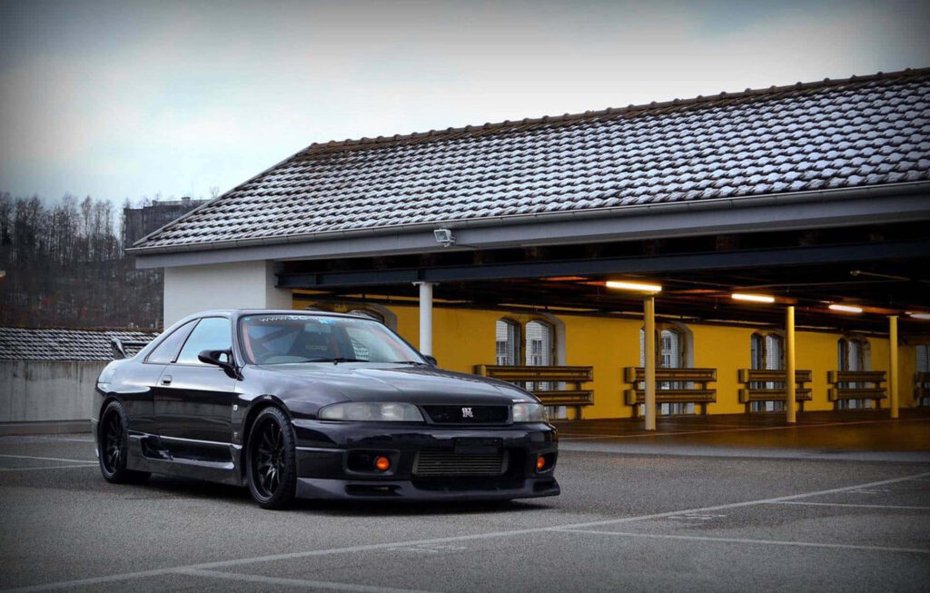 Sleek Nissan R33 GTR Urban Wallpaper with Vibrant Train Station