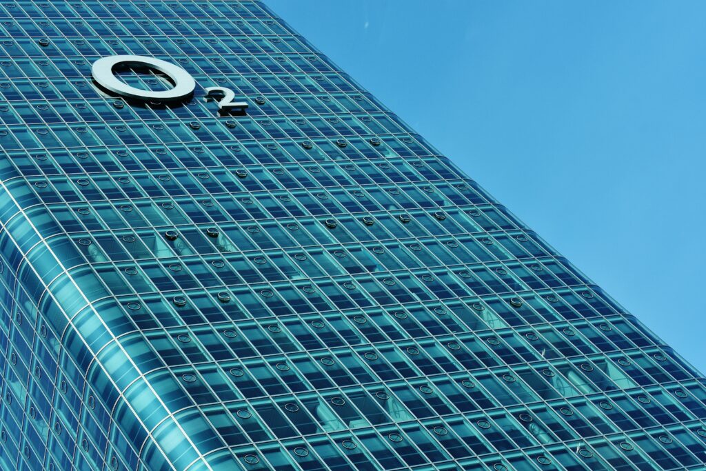 Modern O2 Tower Wallpaper: Sleek Facade Against Blue Sky Background