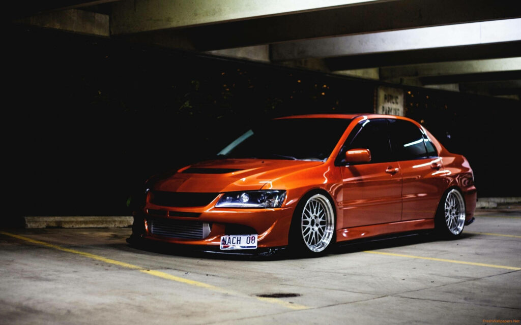Stunning Orange Mitsubishi Evolution Wallpaper in Dim Parking Structure