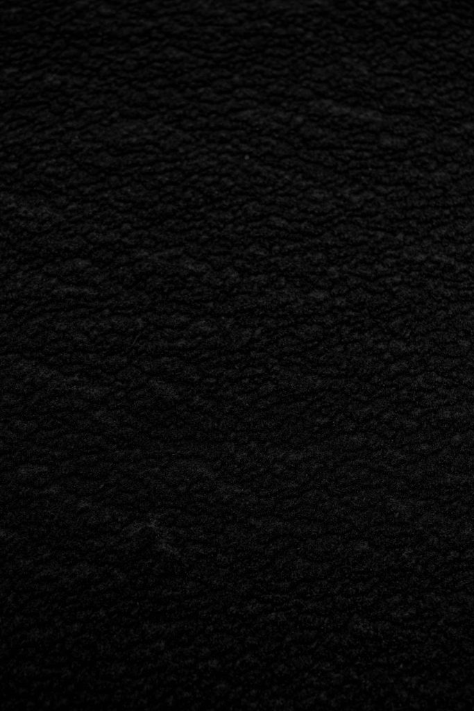 Sleek pure black phone wallpaper with detailed macro texture resembling fine black sand