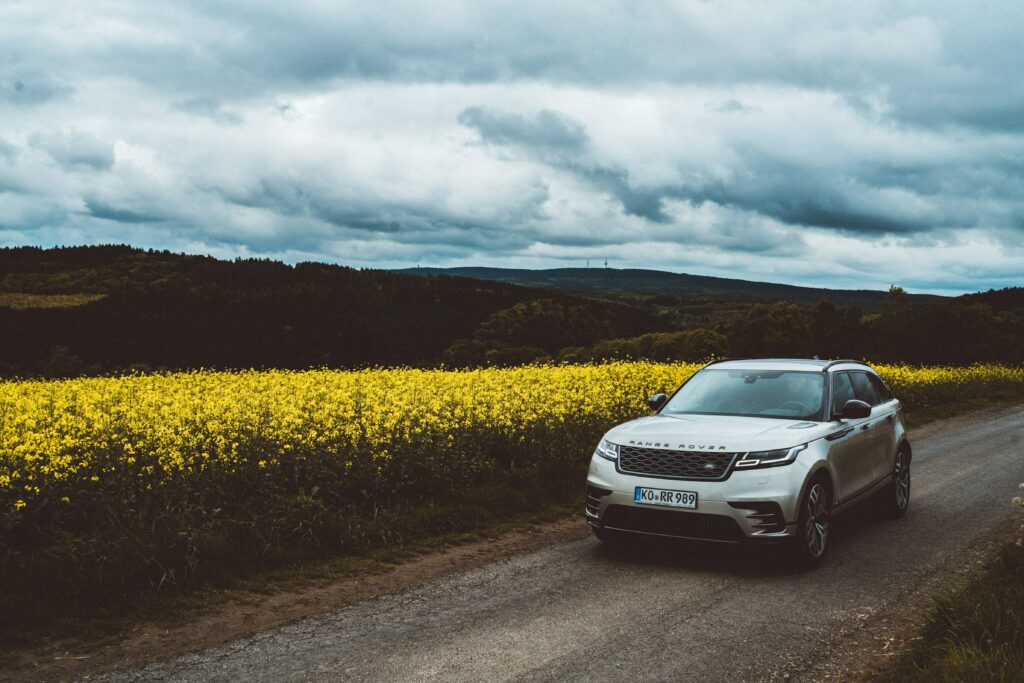 Sleek Range Rover SUV on Scenic Hillside Road with Dramatic Sky Wallpaper