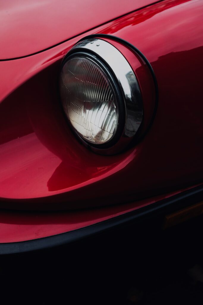Close-Up of Elegant Car Headlight: Sleek Red & Shiny Chrome Details Wallpaper