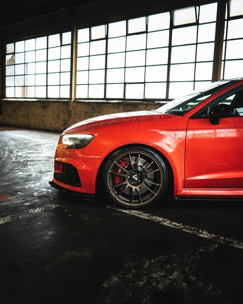 Sleek Red Car with Glossy Finish and Intricate Wheel Design Wallpaper