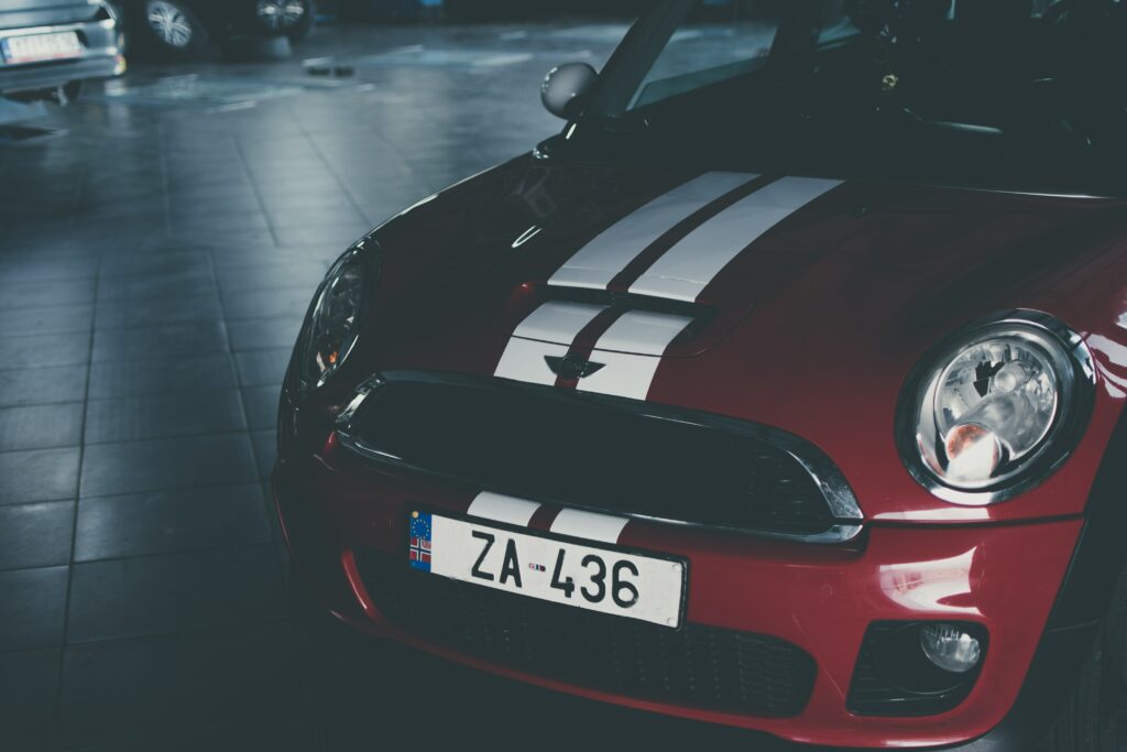 Sleek Red Car Wallpaper: Front View with Racing Stripes & Garage Background