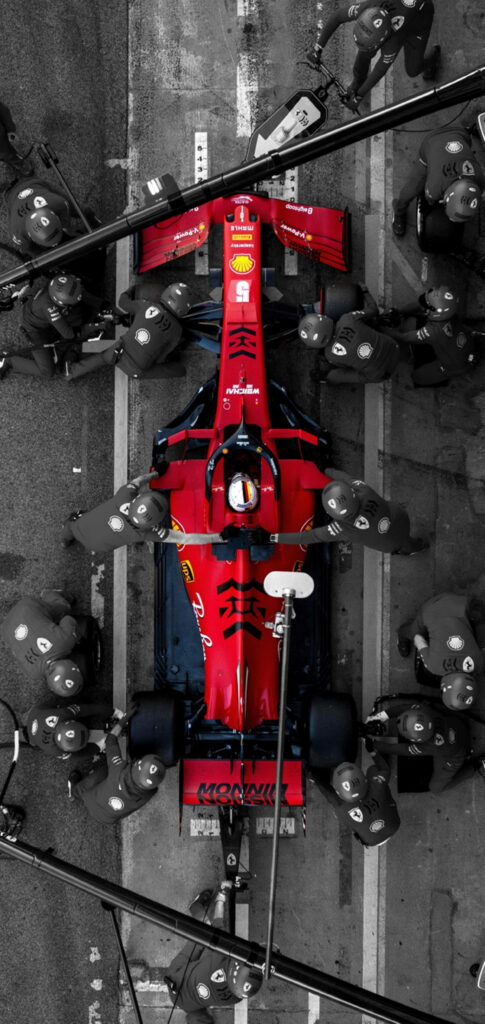 Top view of red Ferrari Formula 1 car in pit stop with crew dynamic motorsport wallpaper background