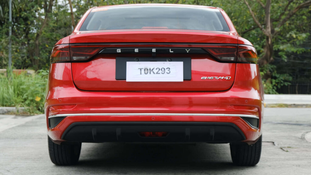 Vibrant Red Geely Emgrand: Sleek Design Against Green Nature Wallpaper