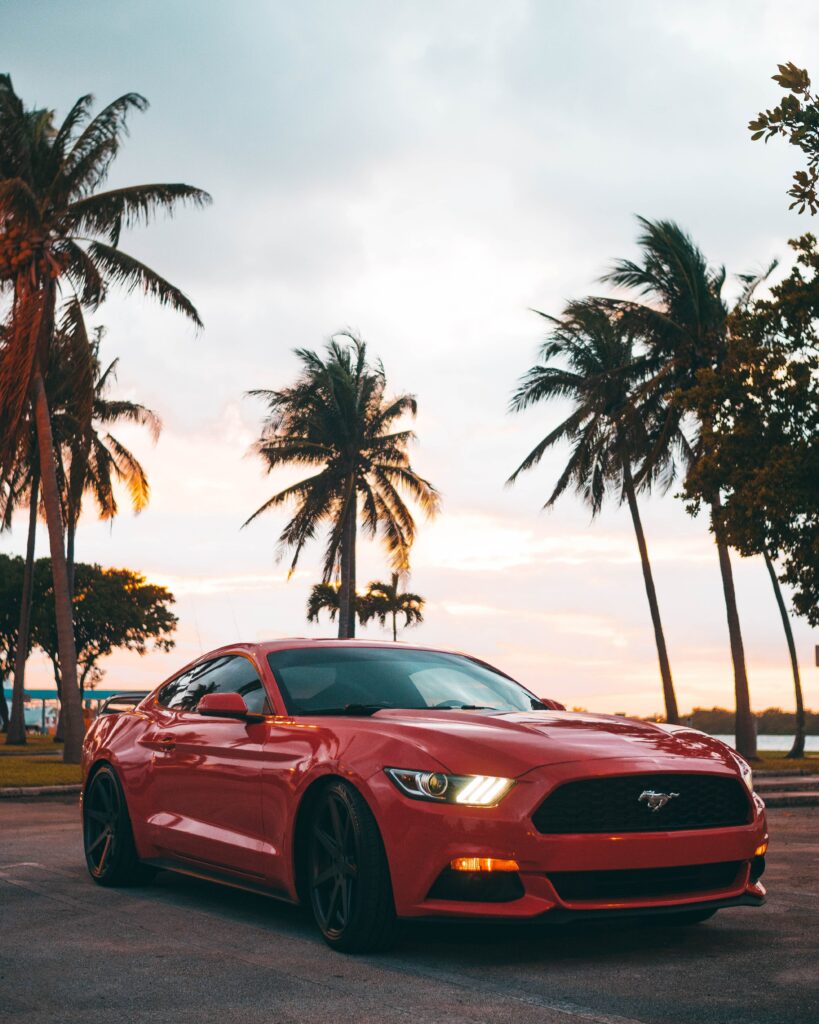 Sleek Red Mustang Wallpaper with Palm Trees & Vibrant Sunset Background
