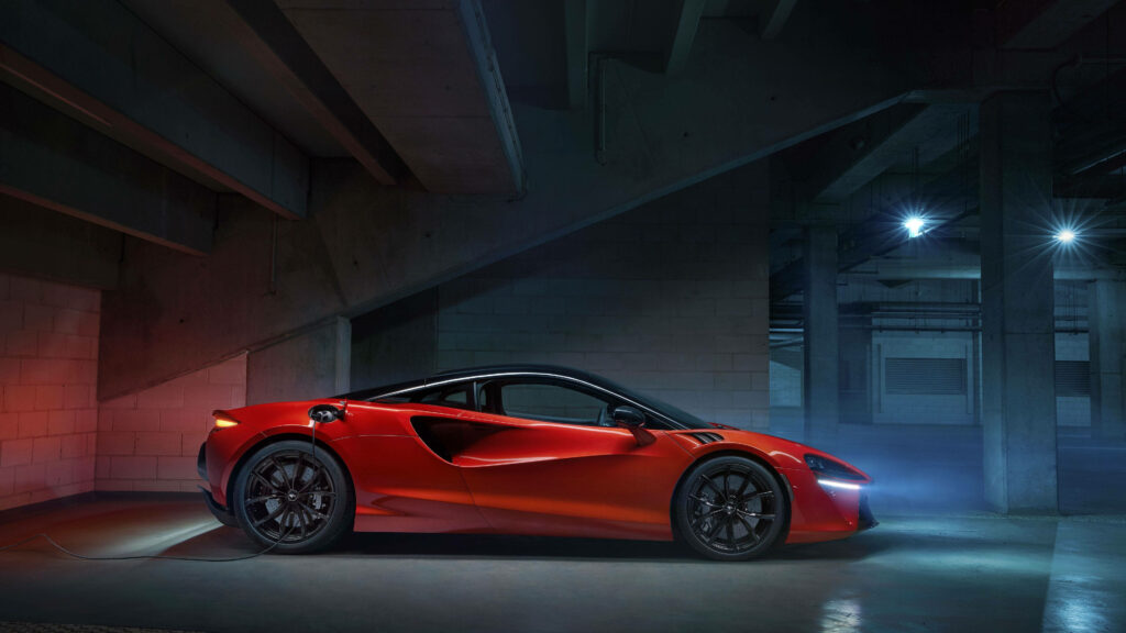 Sleek red sports car parked in dimly lit lot with dramatic lighting showcasing sharp lines Wallpaper