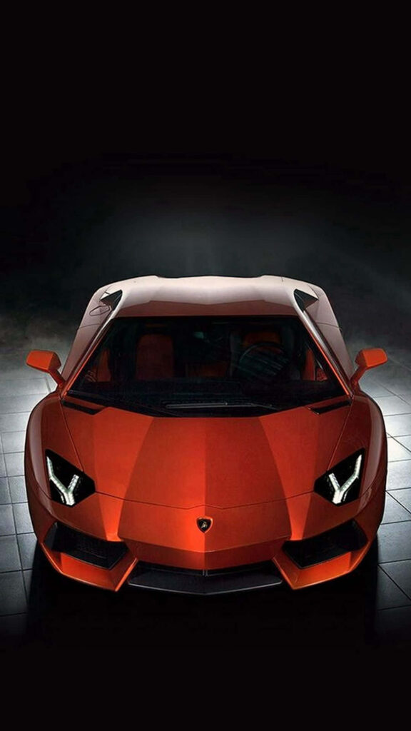 Red sleek sports car with sharp headlights parked in dimly lit modern luxury garage wallpaper