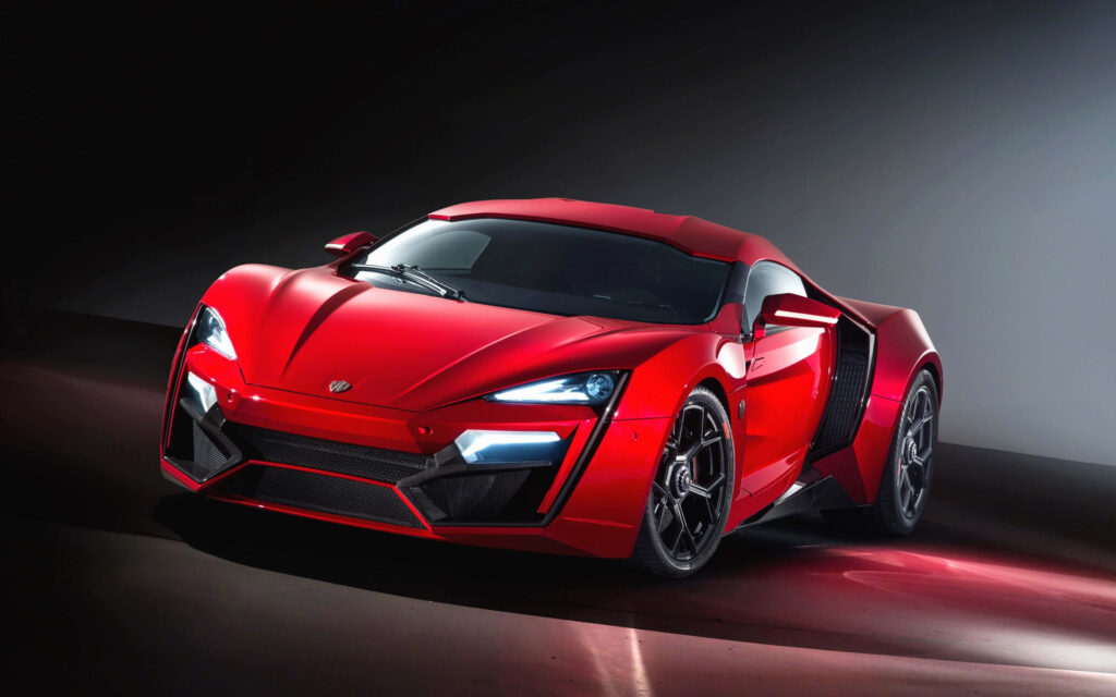 Sleek red sports car with sharp lines in dimly lit room modern design wallpaper background
