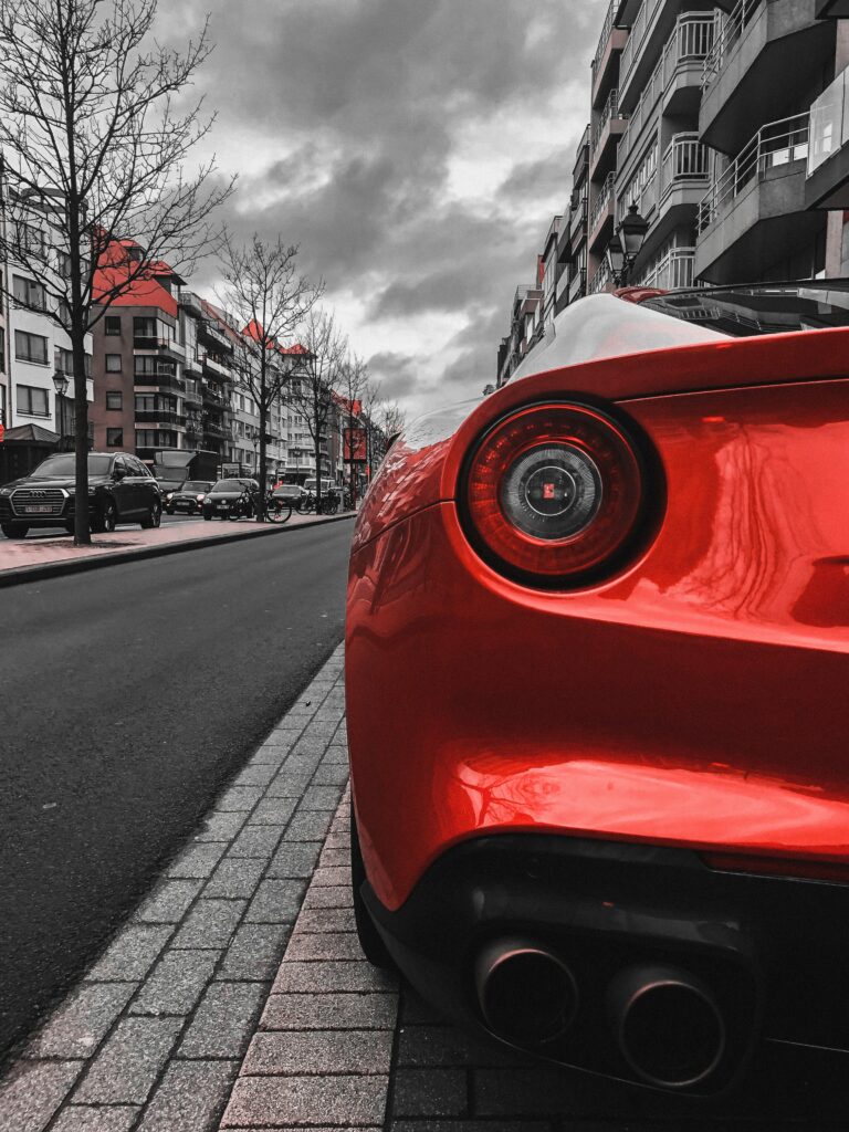 Sleek Red Sports Car Rear View: Urban City Street Wallpaper