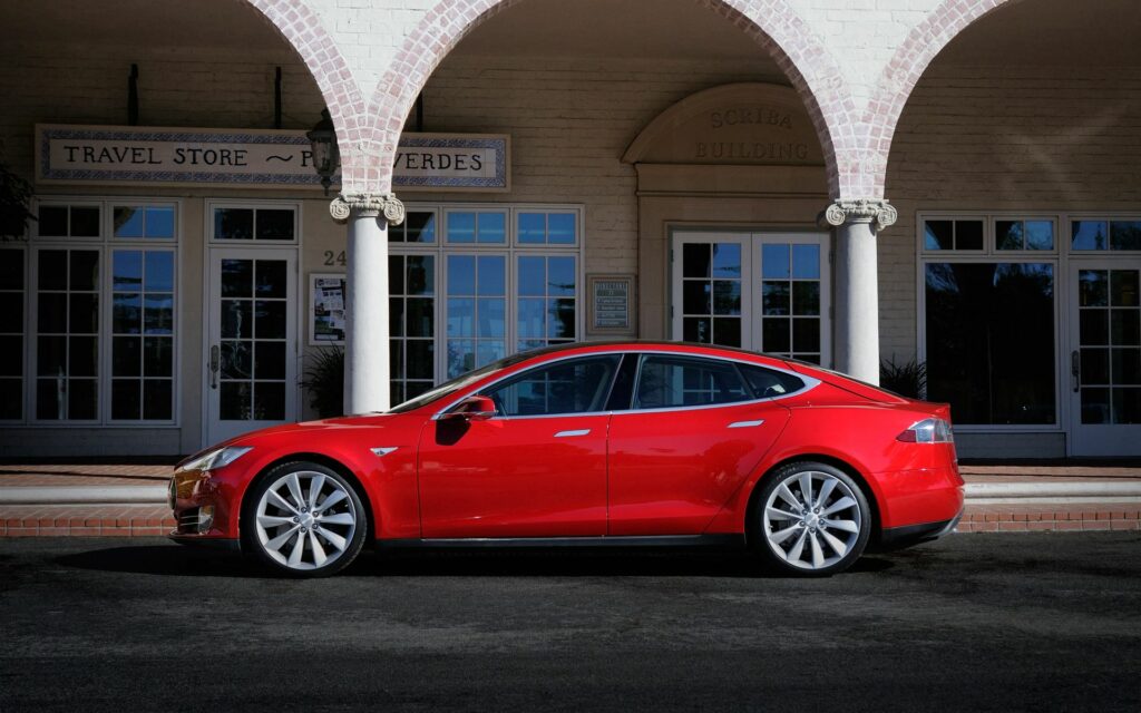 Sleek Red Tesla Model S Wallpaper with Classic Architecture Background