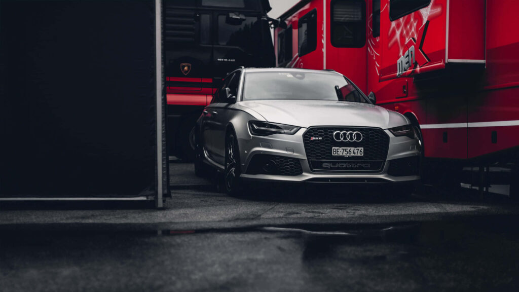 Sleek silver Audi sports car between red vehicles modern design dynamic automotive scene wallpaper