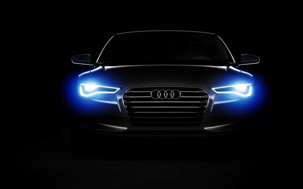 Silver Audi with LED headlights and signature grille in dark background showing luxury speed Wallpaper