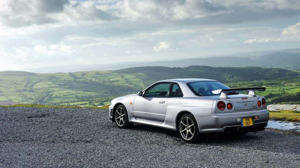 Sleek Silver Nissan Skyline GT-R on Gravel in Lush Landscape Wallpaper