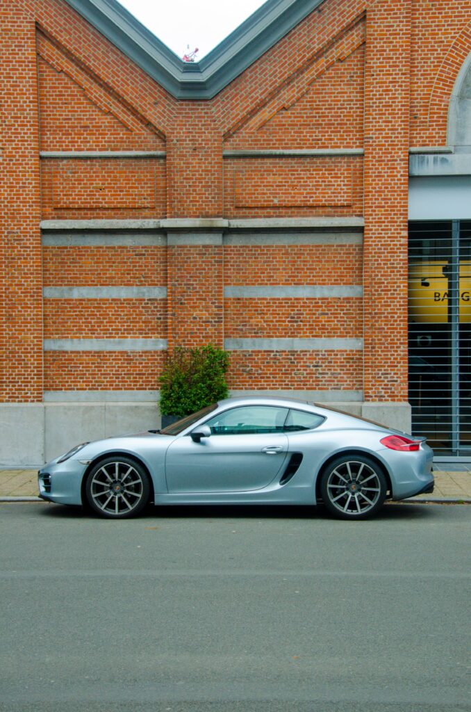 Sleek Silver Sports Car Side View Against Brick Building Backdrop Wallpaper