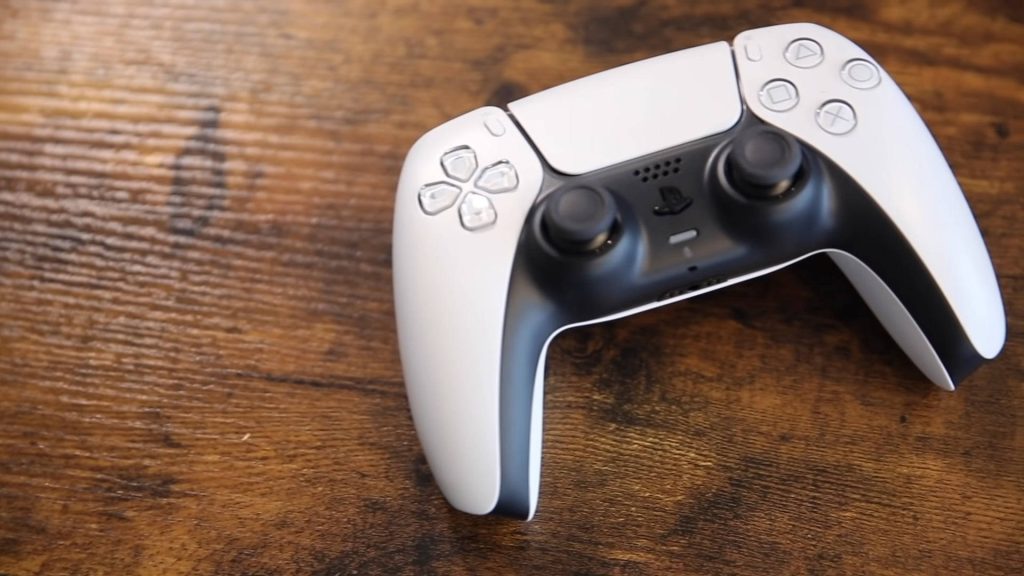 White and black Sony PS5 DualSense controller on rustic wooden desk in natural light wallpaper background
