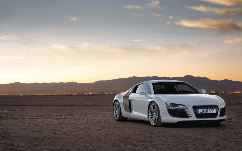 White Audi R8 sports car parked with urban skyline at sunset modern design wallpaper background