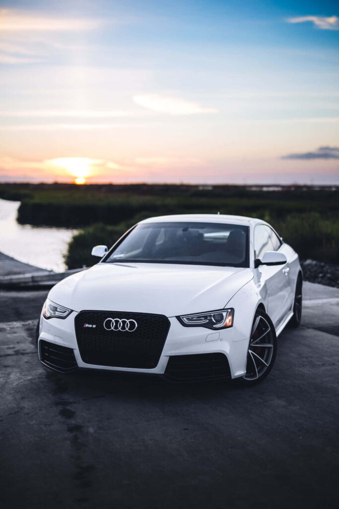 Sleek white Audi parked by waterfront at sunset showcasing modern design and elegance wallpaper