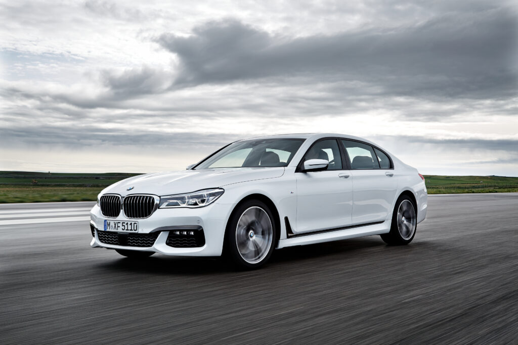 Sleek White BMW 750Li Side View Wallpaper with Cloudy Sky Background