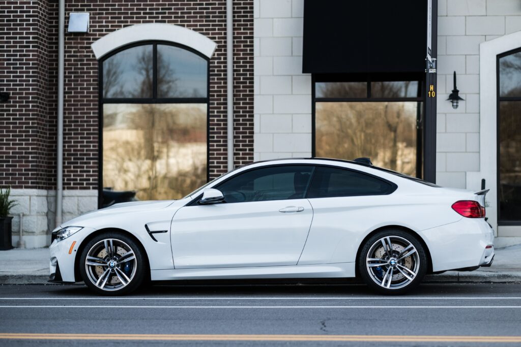 Sleek White Car Side View Against Modern Brick Building Wallpaper