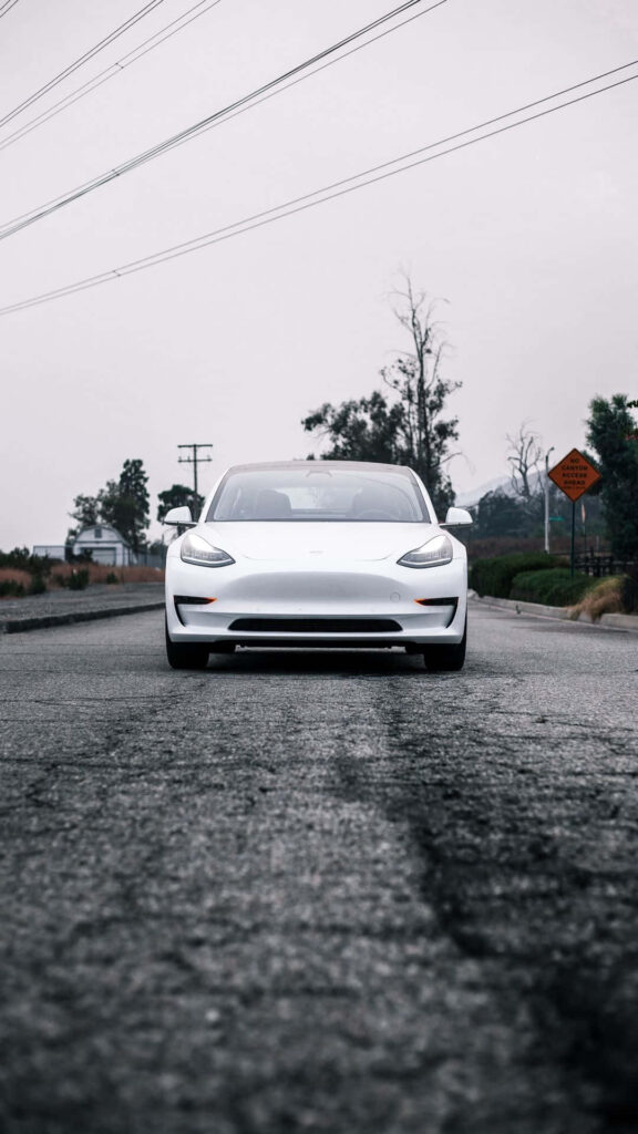 Sleek white modern car on empty road with confident presence and stylish aerodynamic design Wallpaper