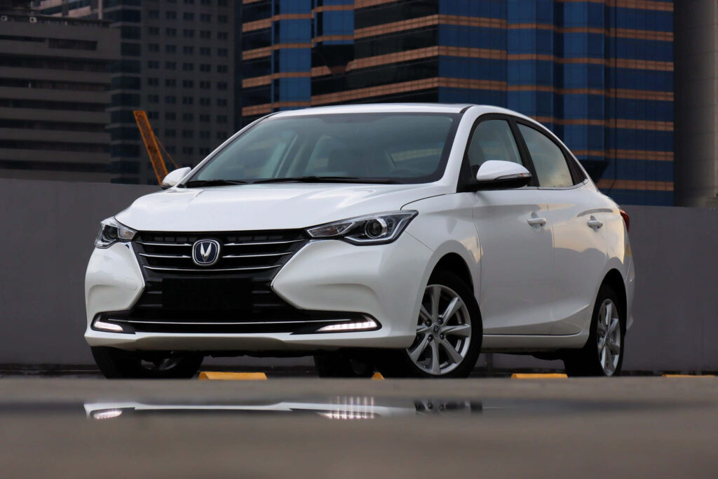 White Changan sedan parked in cityscape with modern high-rise buildings and natural lighting wallpaper