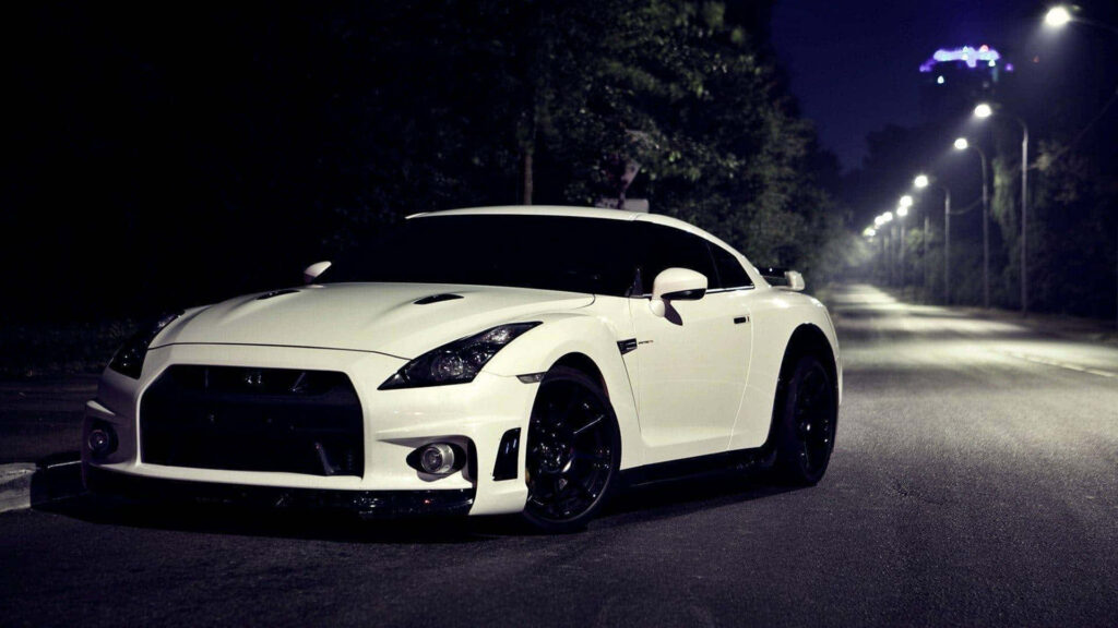 White Nissan R35 GTR parked at night on quiet tree-lined road under soft streetlights wallpaper
