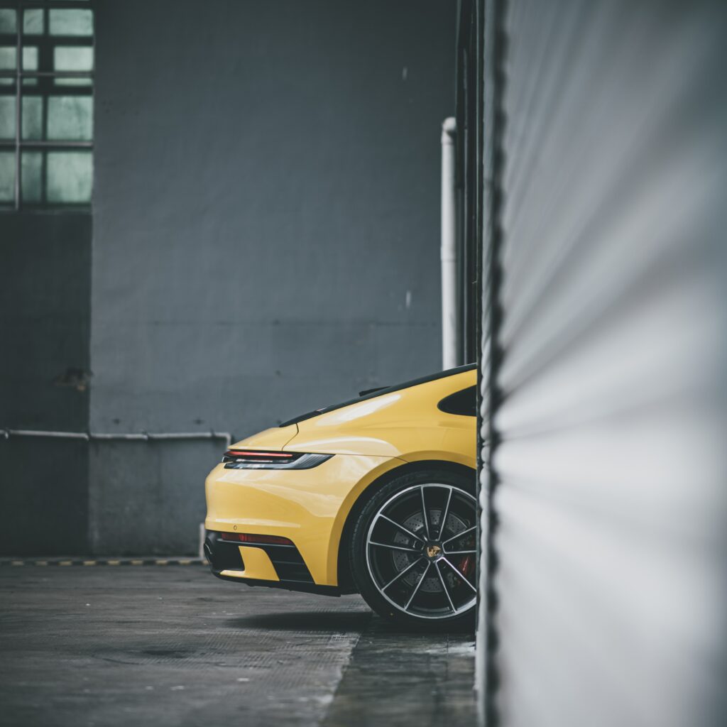 Vibrant Yellow Sports Car: Side View in Industrial Background Wallpaper