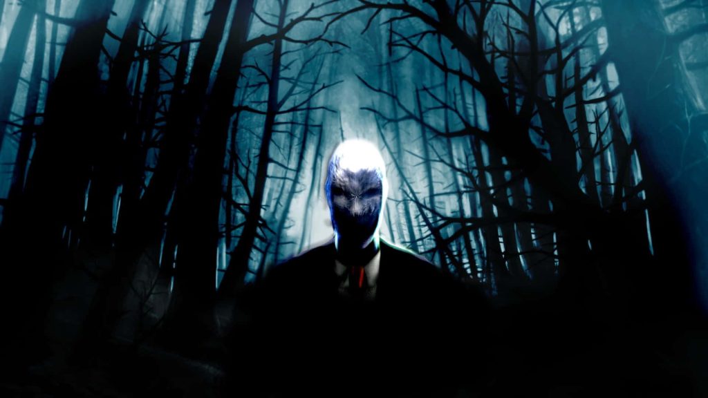Slender Man-inspired figure in dark forest with blue tones and eerie high-contrast lighting wallpaper