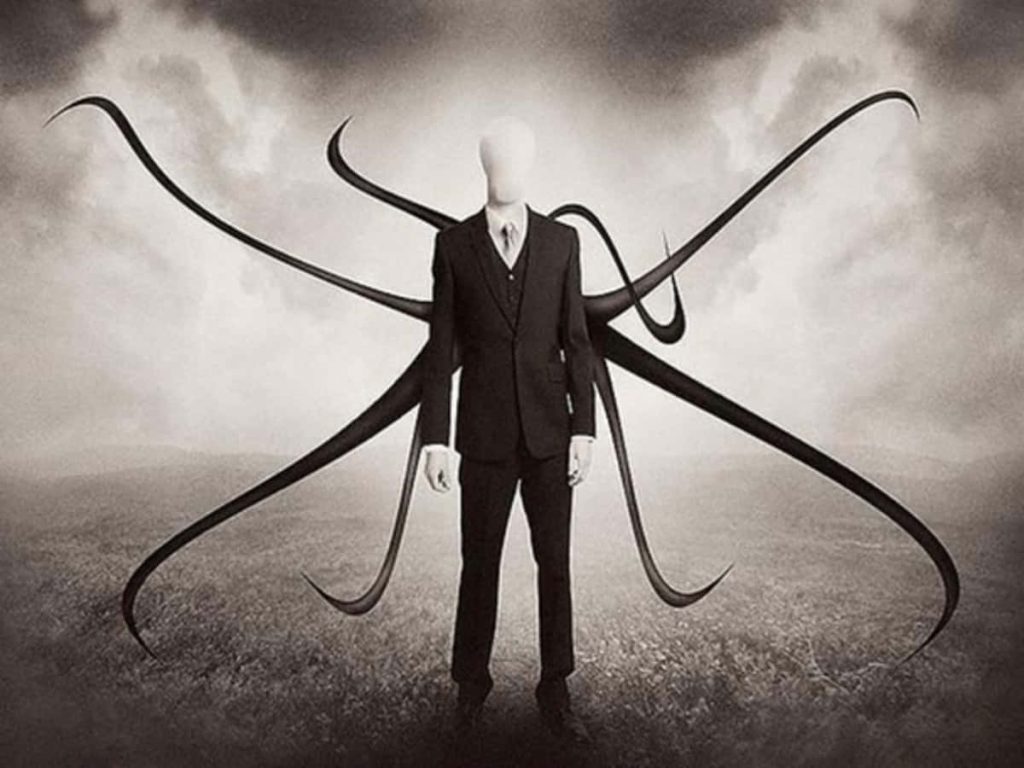 Slender Man in black suit with long tentacles in eerie field under dark cloudy sky wallpaper