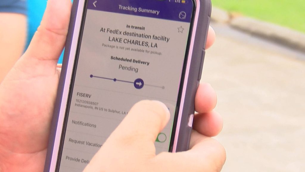 Smartphone showing FedEx tracking app with package status and Lake Charles LA destination details Wallpaper