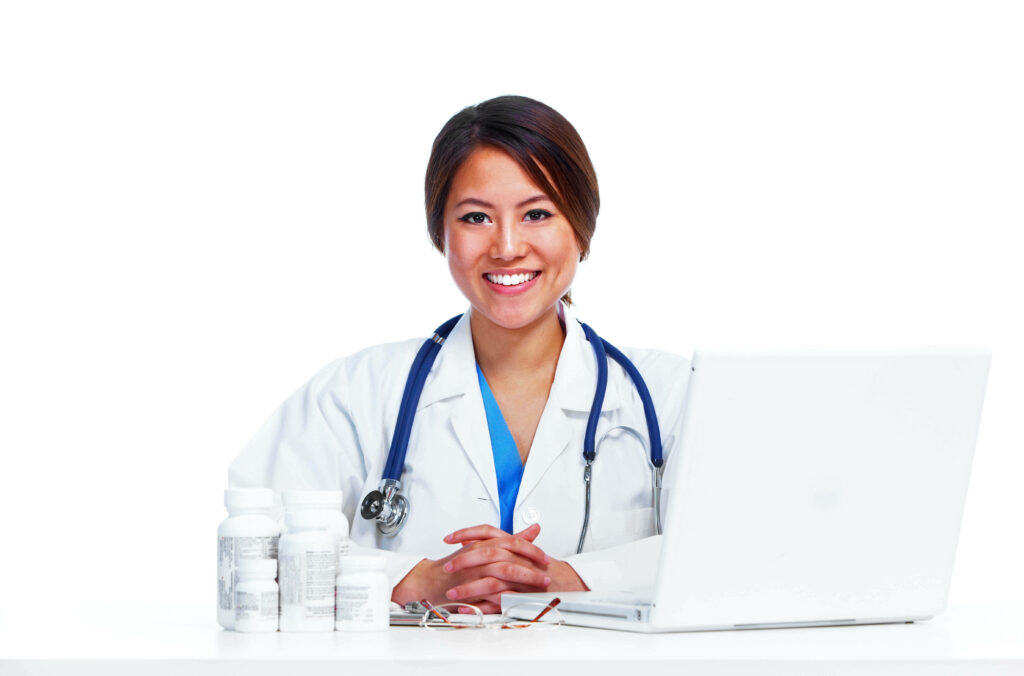 Smiling doctor in white coat with stethoscope at desk with laptop and medicine bottles background Wallpaper