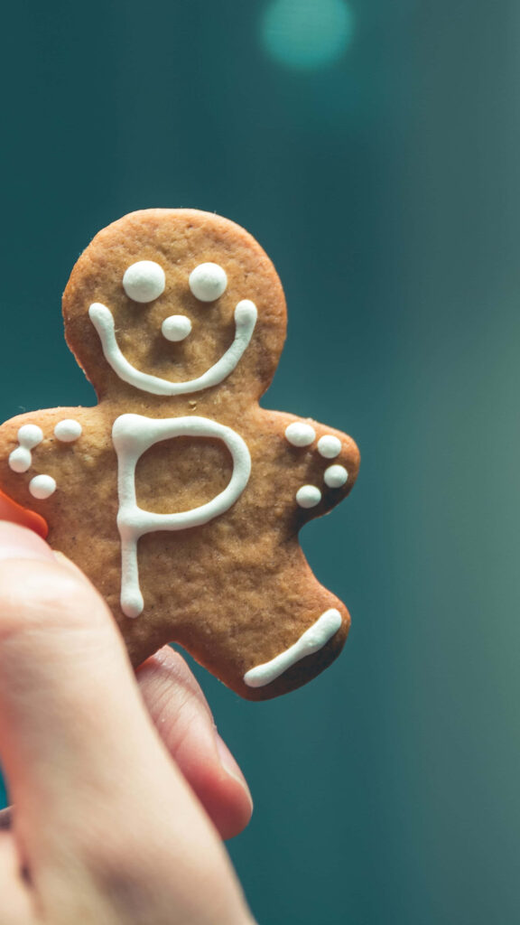 Smiling Gingerbread Cookie with Letter P on Teal Background Wallpaper