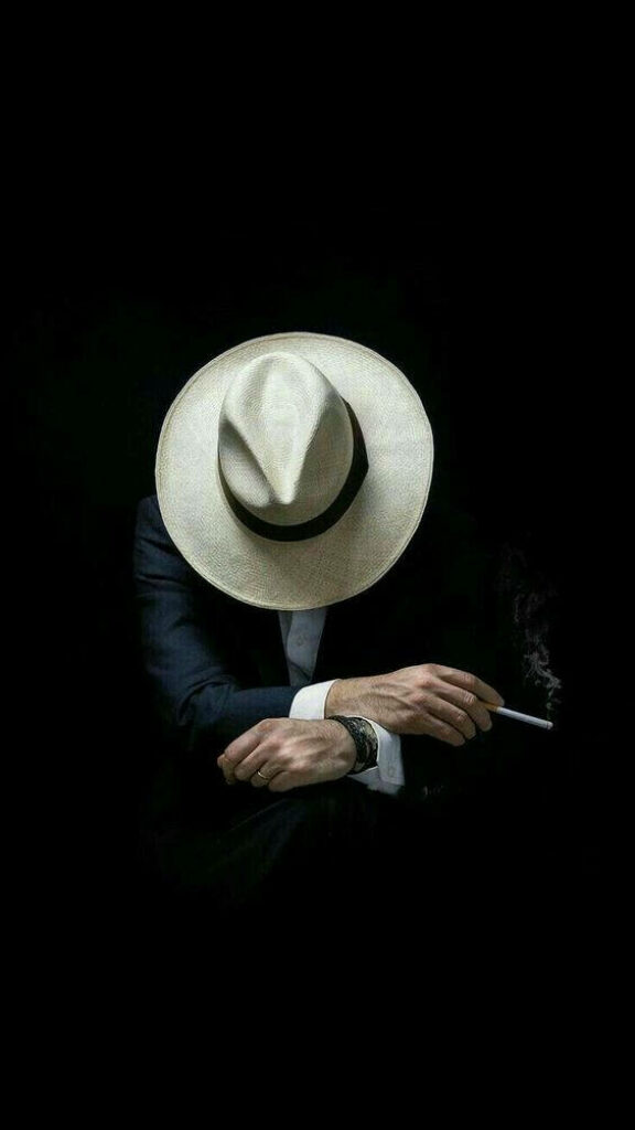 Rebel Charm: Mysterious Man Concealed by White Hat, Embracing a Cigarette Wallpaper