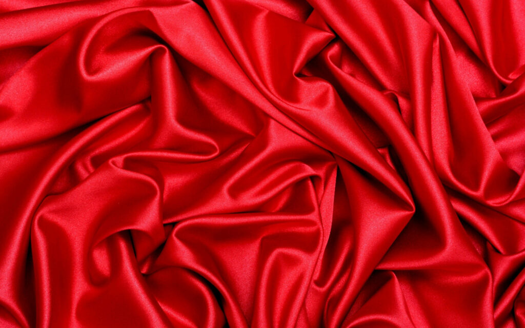 Luxurious red silk wallpaper with glossy deep folds creating elegant flowing waves background
