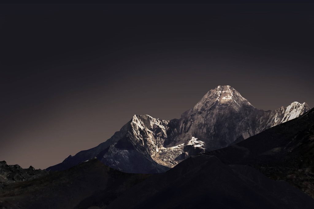 Snow-capped jagged mountain peaks under deep night sky high-contrast cold serene wallpaper