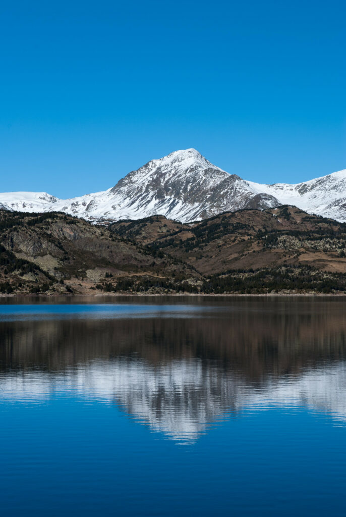 Snow-capped mountain reflected in calm lake under clear blue sky peaceful nature wallpaper