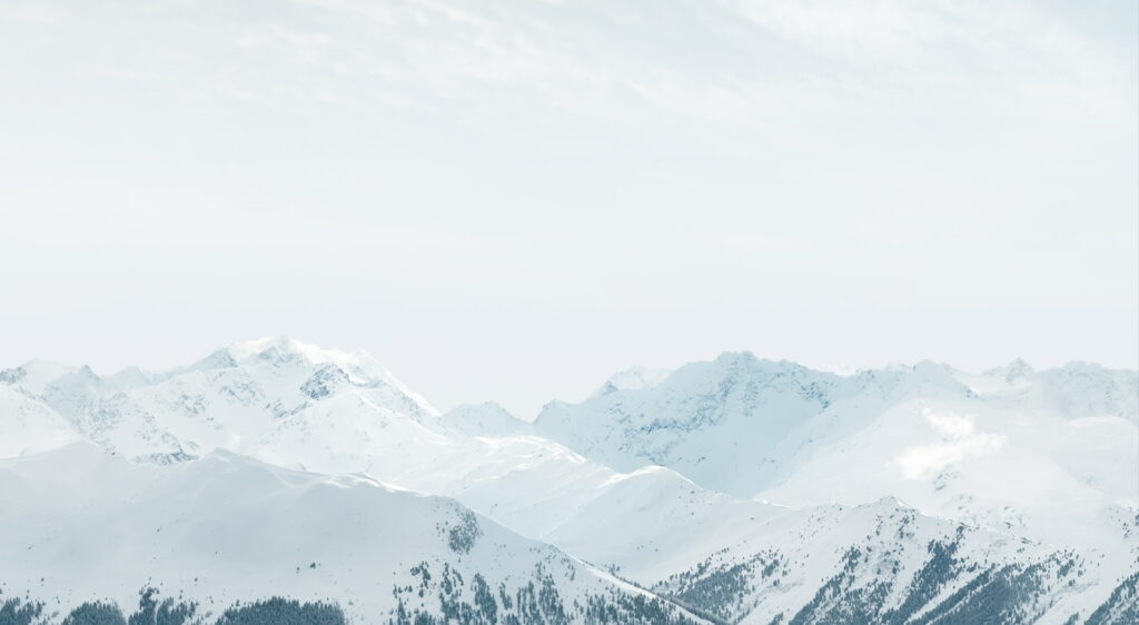 Minimalist snow-capped mountain range wallpaper with bright light for calming desktop background