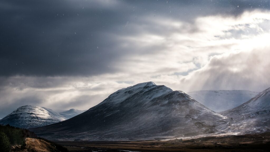 Snow-capped mountains with fog and dramatic clouds creating a serene atmospheric landscape wallpaper