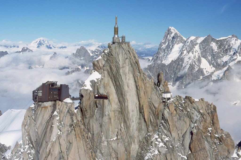 Snow capped rocky mountain peaks with mysterious structure and alpine plants under clear sky wallpaper