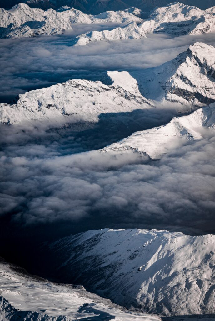 Aerial view of snow-covered mountains with dramatic ridges and clouds serene wallpaper background