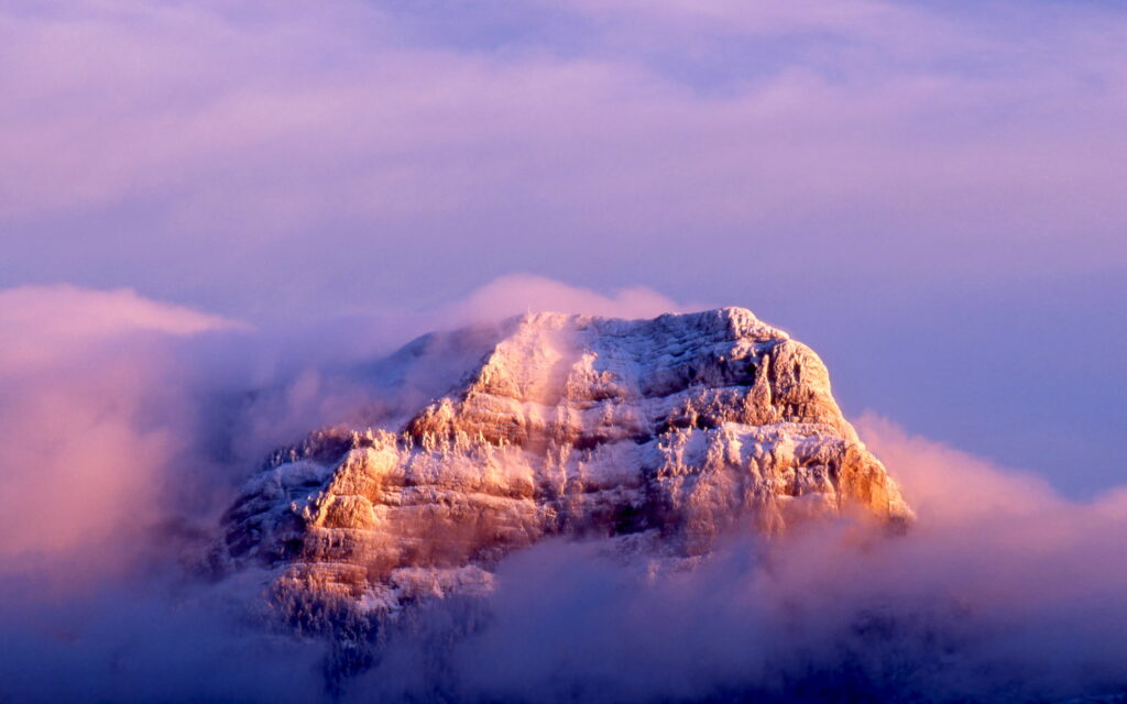 Snow-dusted mountain peak at golden hour with pink clouds in serene alpine landscape wallpaper