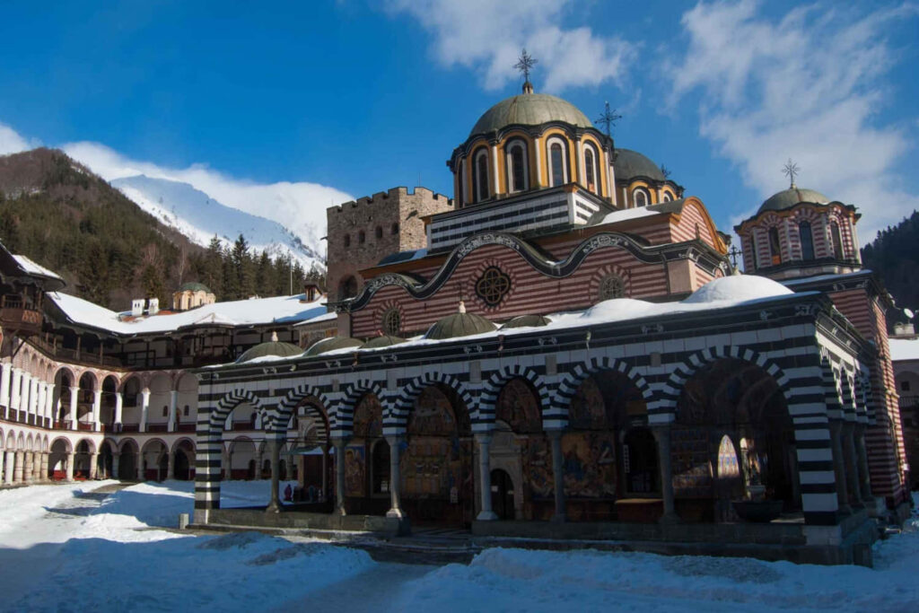 Snow-covered Rila Monastery Bulgaria colorful domes ornate arches mountain winter sky wallpaper