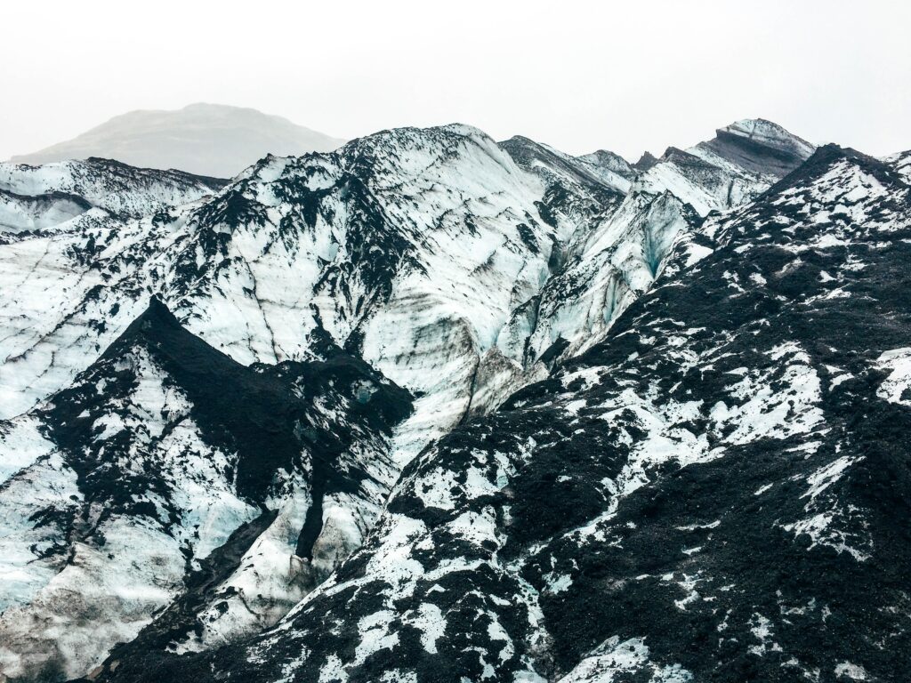 Snow-covered rugged mountain peaks with rocky surfaces in a dramatic wintry alpine landscape Wallpaper