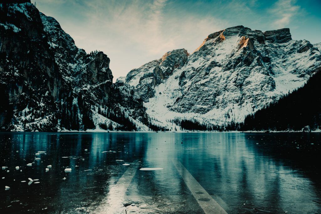 Snow-capped Italian mountains reflecting on icy lake at sunset serene frozen landscape wallpaper