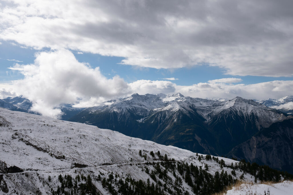 Snow-capped mountain peaks and rocky slopes under dramatic cloudy sky winter alpine landscape wallpaper