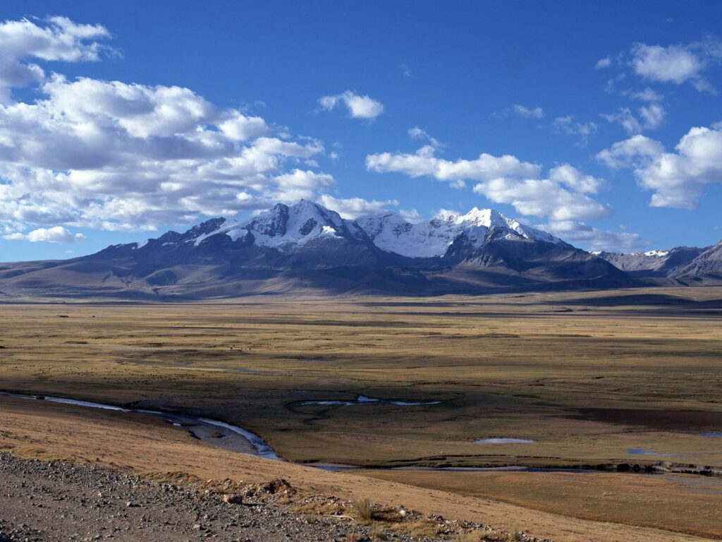 Snow-capped mountains under blue sky with clouds above golden plain and winding stream wallpaper
