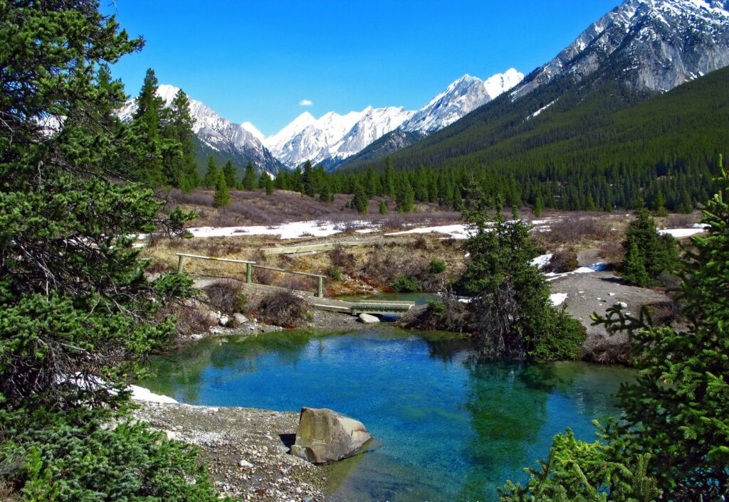 Breathtaking mountain landscape with snow-capped peaks lush pine trees and clear spring water Wallpaper